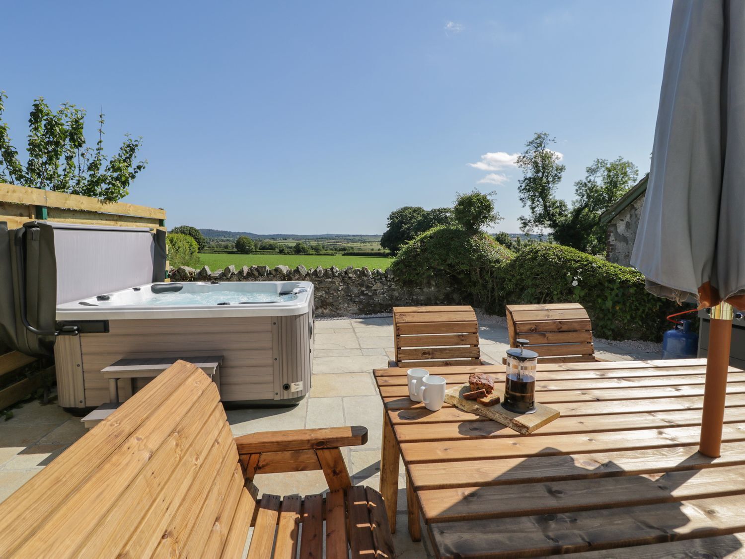 Un espace extérieur aménagé avec des bancs en bois et un jacuzzi, offrant une vue sur un paysage pittoresque.