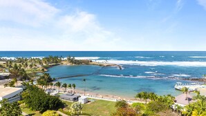 A coastal resort with a beachfront, palm trees, and a clear view of the ocean. - Stylish 1BR with Balcony & Prime Location (San Juan)