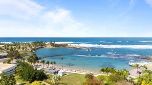 A coastal resort with a beachfront, palm trees, and a clear view of the ocean. - Bright & Modern Suite for Couples (San Juan)