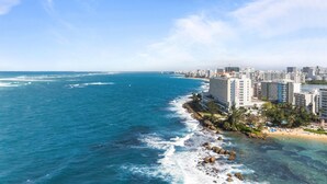 A coastal cityscape with a prominent hotel named 'Condado Plaza' featuring a beachfront location, high-rise buildings, and a clear view of the ocean. - Bright & Modern Suite for Couples (San Juan)