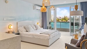 A modern bedroom with a large bed, bedside lamps, a marble bedside table, and a view of the sea through a balcony. - Bright & Modern Suite for Couples (San Juan)