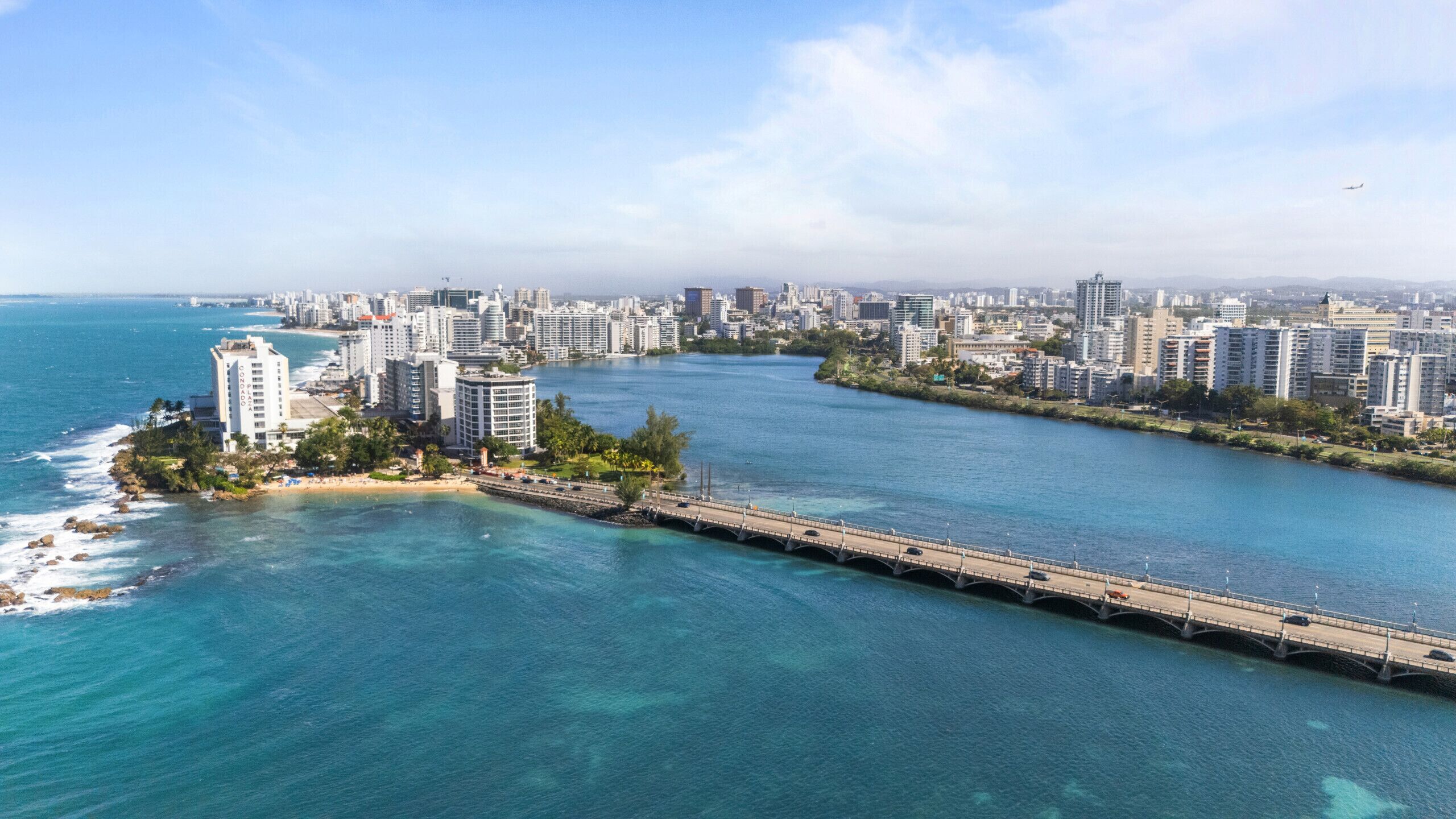 A coastal cityscape with a prominent bridge connecting two land masses.