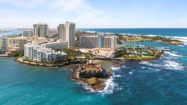 A coastal hotel complex with multiple high-rise buildings, a central courtyard, and a fortified structure. - Bright & Modern Suite for Couples (San Juan)
