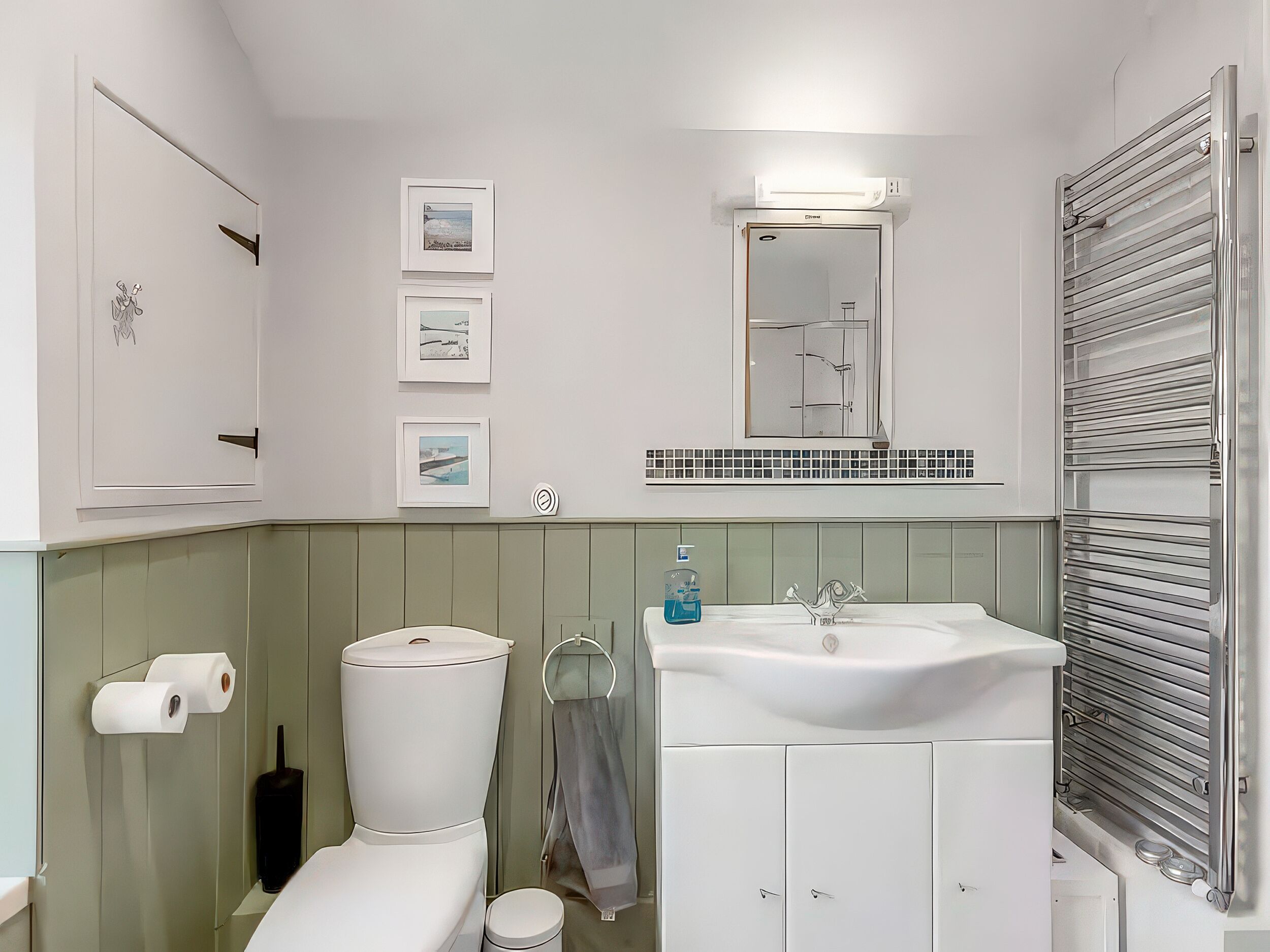 Een badkamer met toilet, wastafel en spiegel. Er hangen prestaties aan de muur en er is een handdoekhouder.