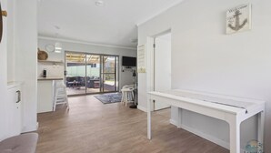 Ein geräumiges Zimmer mit Holzboden, einem weißen Konsolentisch und einer Schiebetür zu einem Balkon.