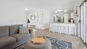 Ein modernes Wohnzimmer mit einem grauen Sofa, einem runden Holztablett und einem grauen Teppich mit Muster.