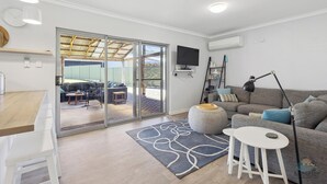 Ein modernes Wohnzimmer mit einem grauen Sofa, einem kleinen weißen Tisch und einem grauen Teppich mit Muster.