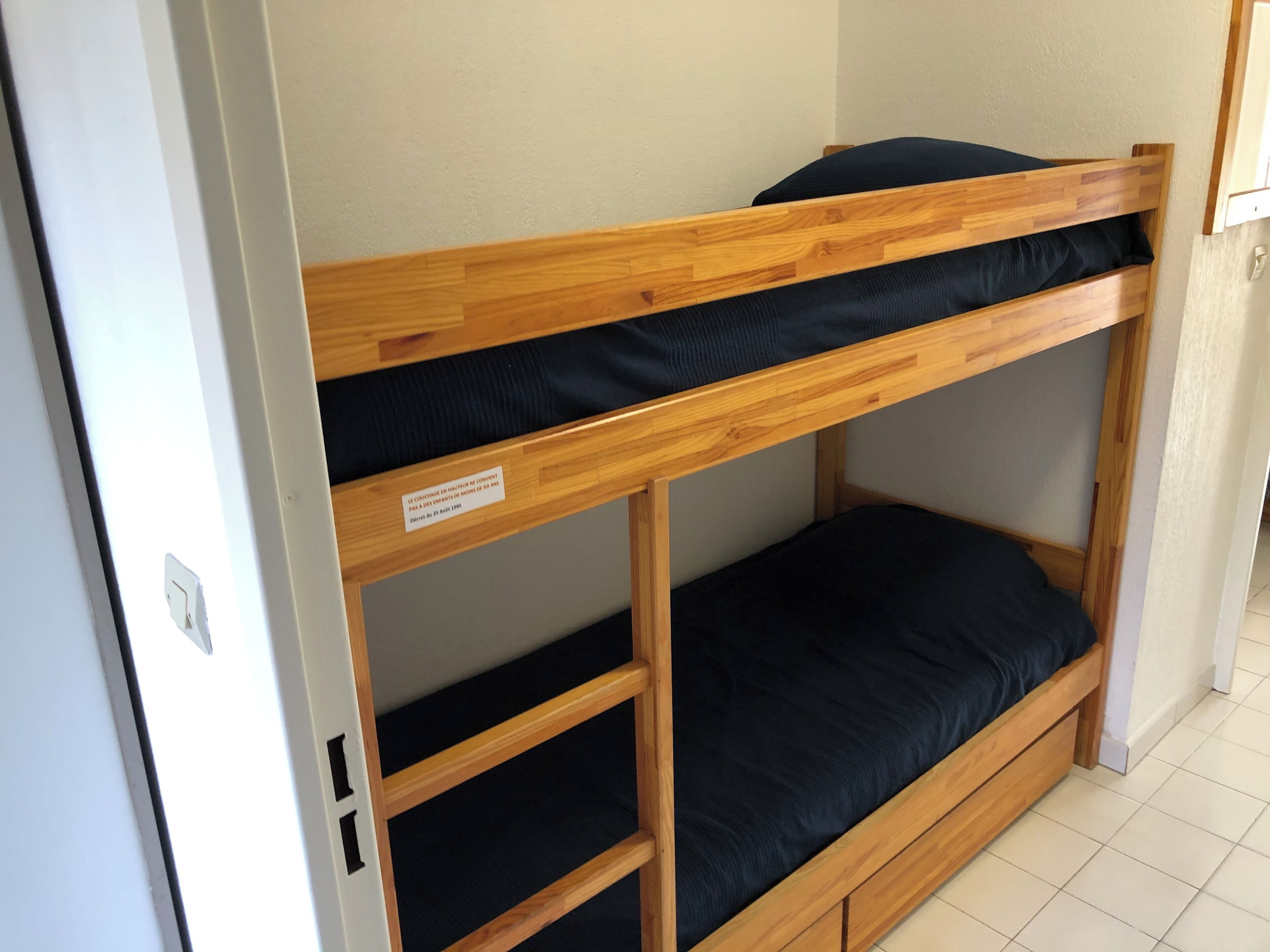 Uma cama beliche com estrutura de madeira e roupa de cama preta.