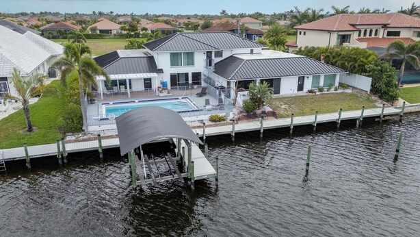 Ein Haus mit Pool, überdachter Terrasse und einer Anlegestelle, die ins Wasser führt.
