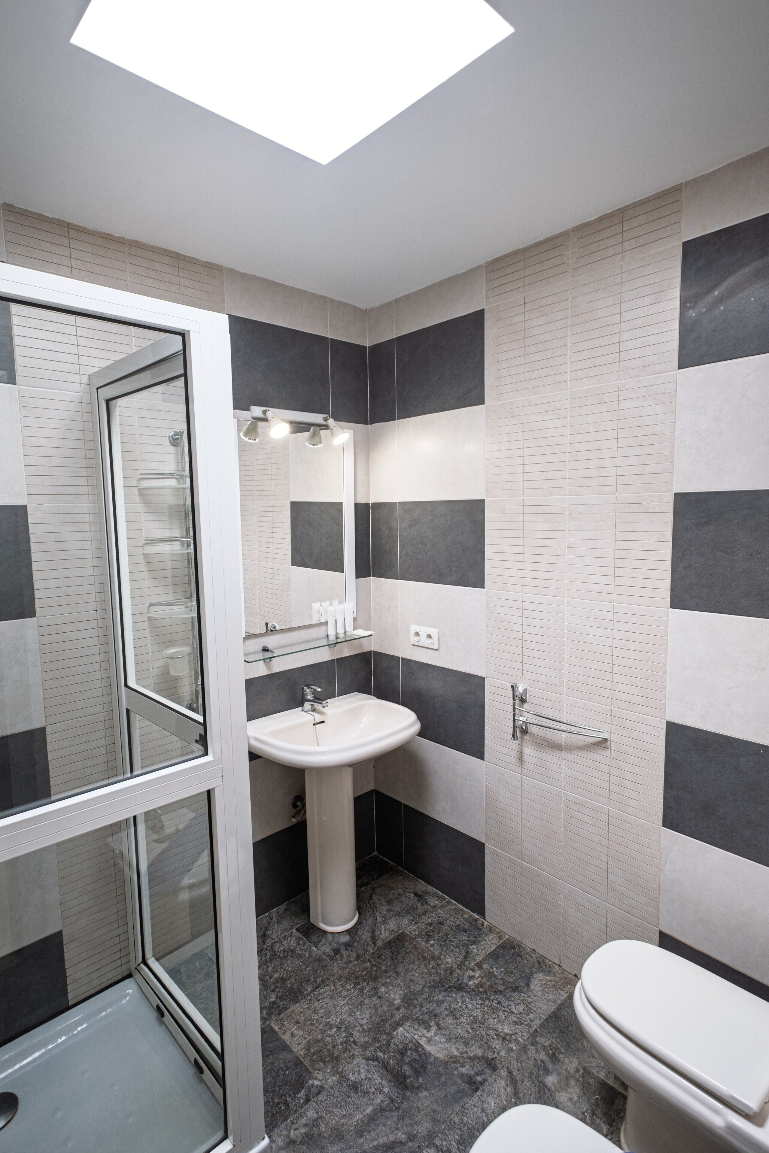 Un baño moderno con cabina de ducha de vidrio, lavamanos sobrepedal y retrete.