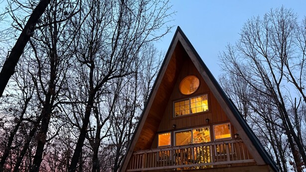 A wooden cabin with a balcony, surrounded by trees. - A Frame Cabin In The Woods (Omaha)