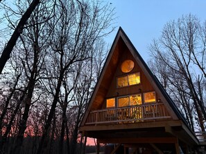 A wooden cabin with a balcony, surrounded by trees. - A Frame Cabin In The Woods (Omaha)