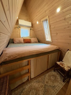 A cozy attic bedroom with a bunk bed, wooden walls, a window, and a ceiling fan. - A Frame Cabin In The Woods (Omaha)