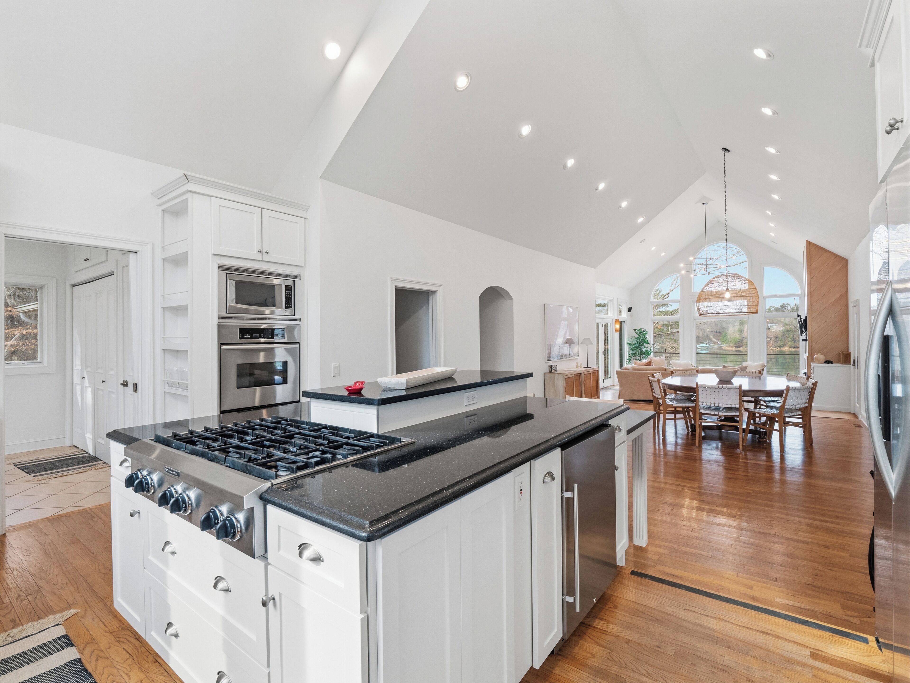 A spacious kitchen with white cabinetry, a central island with a stove, and a dining area with a large table and chairs.