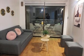 Un soggiorno moderno con un divano grigio, un tavolino rotondo e una pianta in vaso.