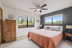 A bedroom with a bed, two windows, a ceiling fan, a dresser, and a nightstand. - Sunset Ridge at Pine Mountain Lake (Groveland)
