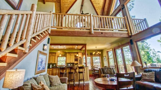 Ein geräumiges Loft mit hohen Decken, einer Holztreppe, einem Essbereich und einer Küche.