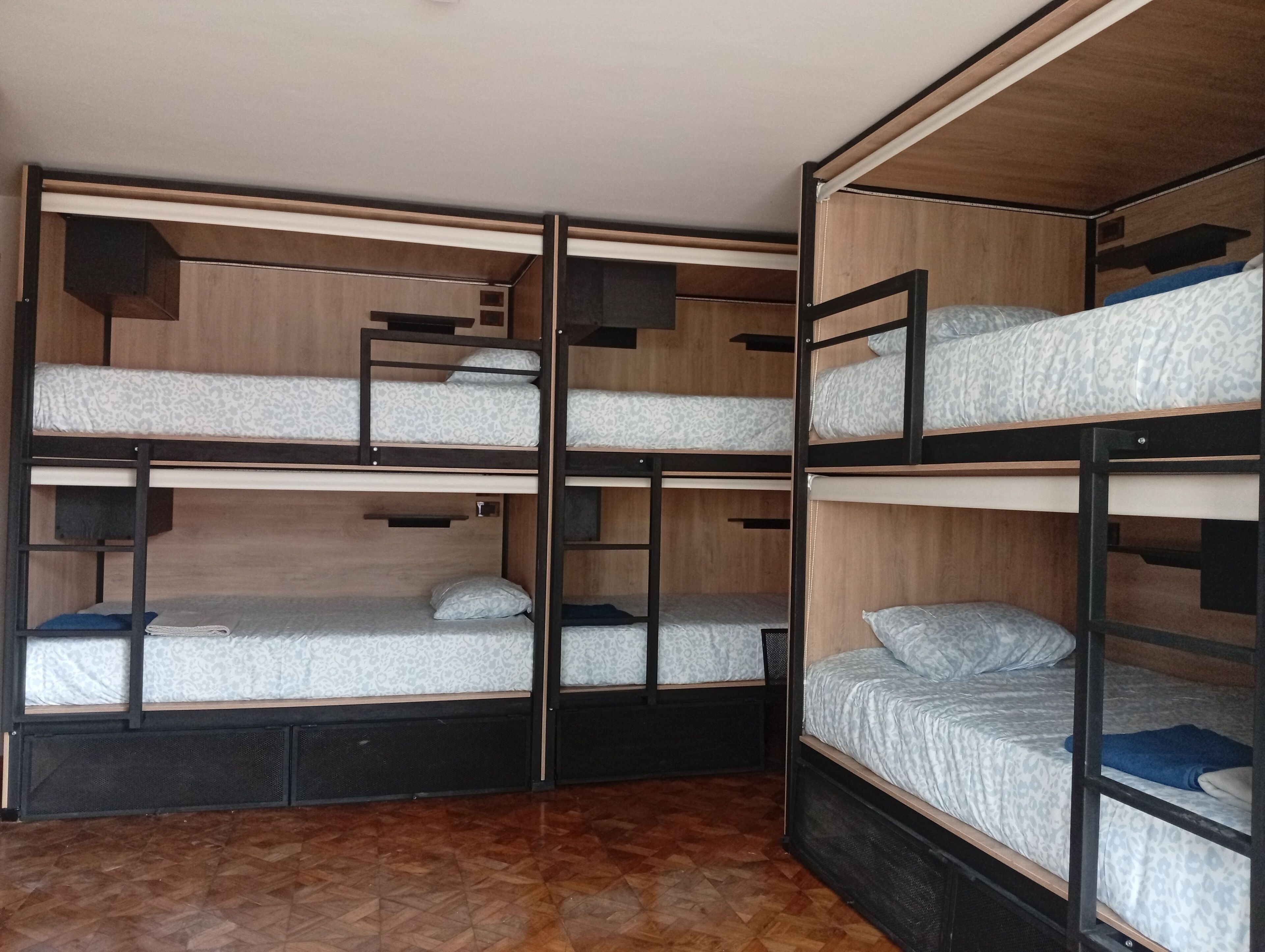 A bunk bed room with three levels, each with a mattress and pillows.