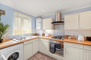A compact kitchen with a washing machine, a stove, and a sink. - Central London Stay | Driveway Parking - Sleeps 6 (London)