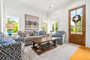 A living room with a wooden coffee table, patterned sofas, and a large painting. - New Luxurious & Elite! Steps to Auburn University & Downtown (Auburn)