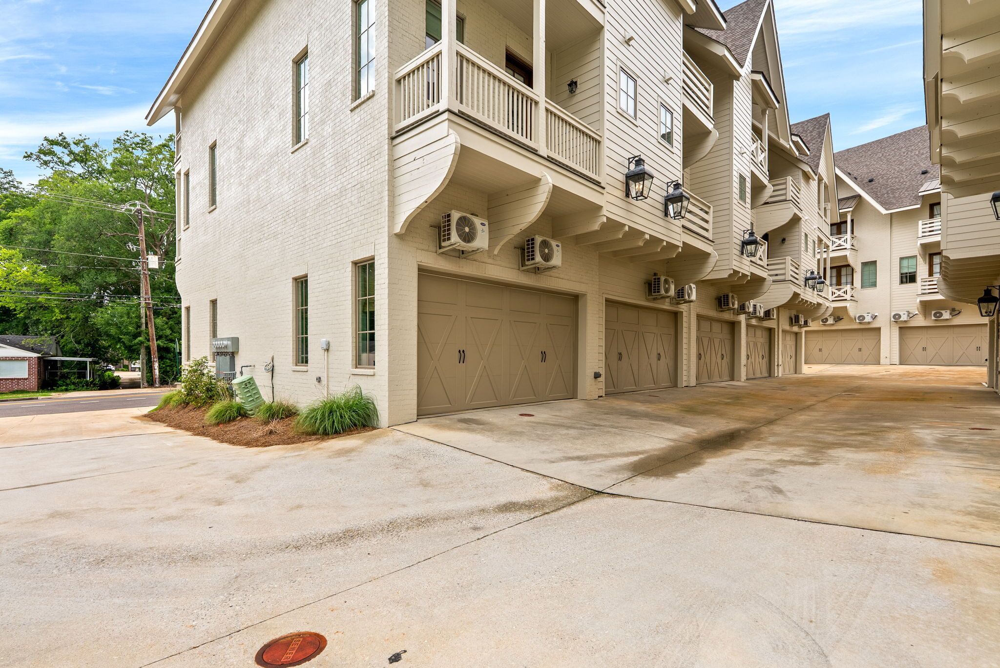A multi-story building with a central garage entrance, multiple balconies, and air conditioning units.