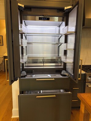 Una cocina moderna con un refrigerador de acero inoxidable integrado, una encimera de madera y una estufa a gas.