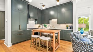 A kitchen with dark cabinets, a wooden table, and bar stools. - New Luxurious & Elite! Steps to Auburn University & Downtown (Auburn)