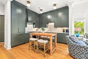 A kitchen with dark cabinets, a wooden table, and bar stools. - New Luxurious & Elite! Steps to Auburn University & Downtown (Auburn)