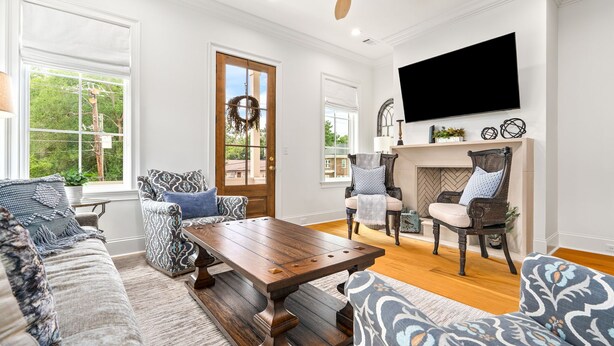 A living room with a wooden coffee table, patterned sofas, a fireplace, and a TV mounted on the wall. - New Luxurious & Elite! Steps to Auburn University & Downtown (Auburn)