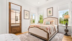 Un dormitorio con cama, puerta, ventana y lámpara.