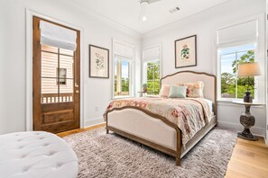 Un dormitorio con cama, puerta, ventana y lámpara.