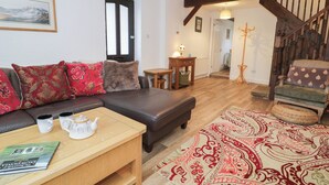 Un salon chaleureux avec un canapé en cuir marron, une table basse en bois et un tapis à motifs.