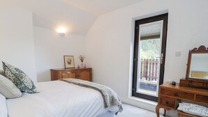Une chambre à coucher comprenant un lit, une commode, un miroir et une fenêtre donnant sur une clôture en bois.