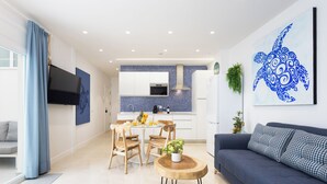 Un espace de vie moderne comprenant un coin repas, une cuisine et une grande œuvre d’art représentant une tortue bleue, accrochée au mur.
