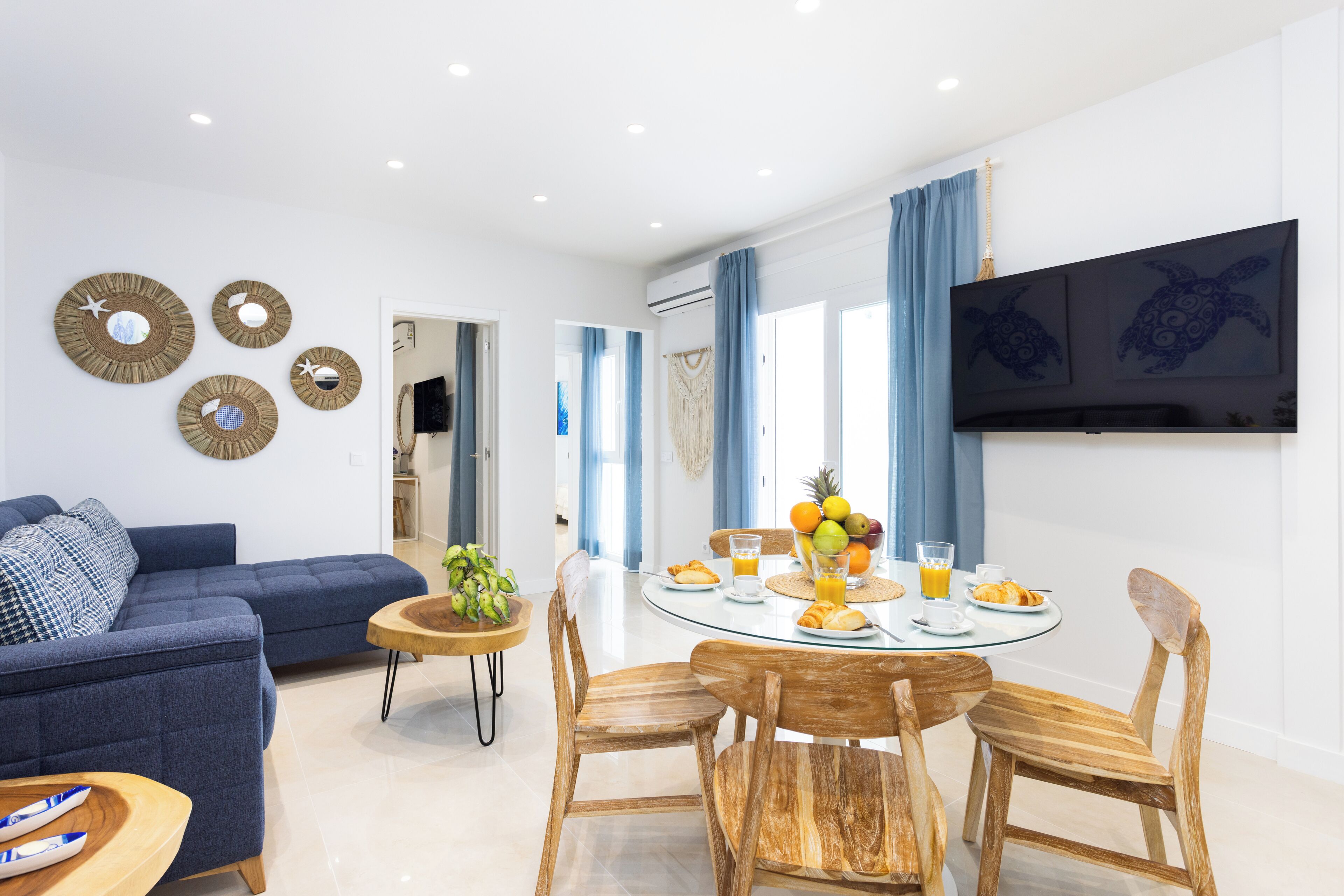 Un salon moderne avec un canapé bleu, une table à manger en bois avec des chaises et des éléments de décoration fixés au mur.