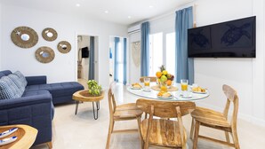 Un salon moderne avec un canapé bleu, une table à manger en bois avec des chaises et des éléments de décoration fixés au mur.