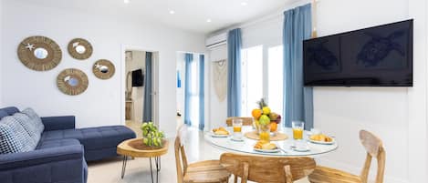 Una sala de estar moderna con un sofá azul, una mesa de comedor de madera con sillas y adornos en la pared.