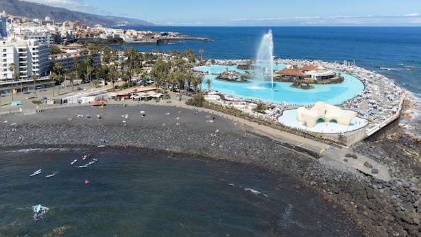 Une station balnéaire dotée d’une vaste plage de sable, d’une piscine centrale et d’une côte rocheuse.