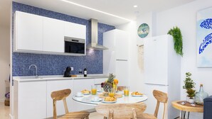 Une cuisine moderne avec des meubles blancs, un pare-feu bleu et un îlot central doté de chaises.