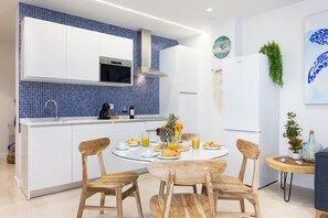 A modern kitchen with white cabinets, blue backsplash, and a central island with chairs. - THE BLUE TURTLE B (Puerto de la Cruz)