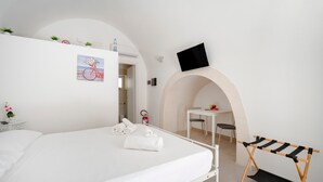 Une chambre d’hôtel avec un lit, un bureau, un téléviseur fixé au mur et une petite table avec une chaise.