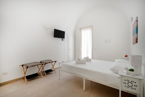 A minimalist bedroom with a bed, a TV, a small table, and a nightstand. - Apartment 'Stella' with Wi-Fi (Mola di Bari)
