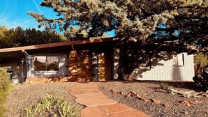 A modern house with a stone exterior, a wooden deck, and a gravel pathway leading to the entrance. - Coffee Pot Trailhead Bungalow, Red Rock Views, Private Patios, Red Rock Pass (Sedona)