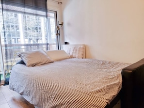 Ein Schlafzimmer mit Bett, Fenster und Heizkörper.