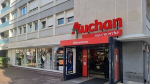 Ein Supermarkteingang mit einem roten Schild und einem Willkommensschild.
