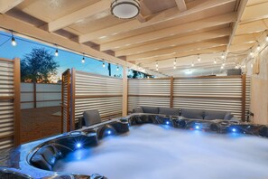 Een bubbelbad met stoom, houten balken en lichtjes.