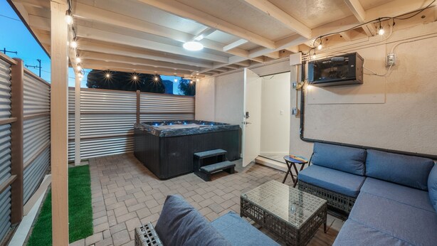 An outdoor patio with a hot tub, seating area, and a TV mounted on the wall. - Tucson 18th Street A B (Tucson)