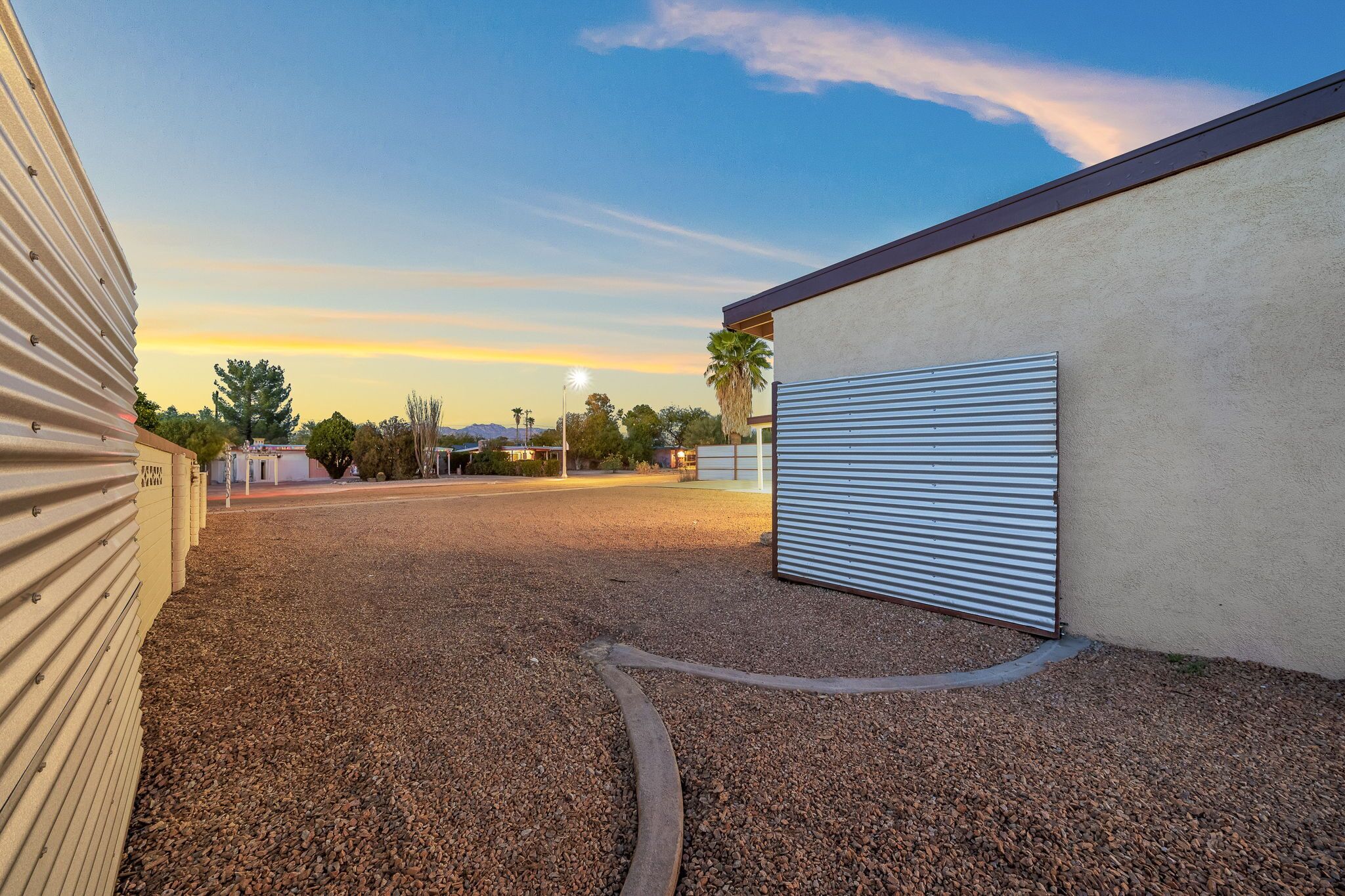 A gravel driveway leading to a building with a closed metal garage door.