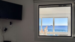 Une pièce dotée d’une grande fenêtre donnant sur la mer et sur un navire.