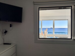 Ein Zimmer mit großem Fenster und Blick auf das Meer sowie ein Schiff.